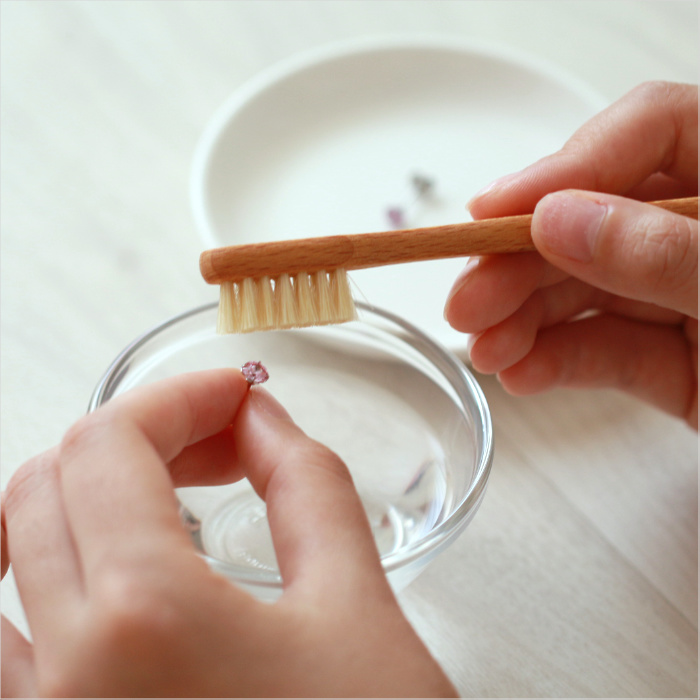 ジュエリー用ブラシでピアスの汚れを取っている画像