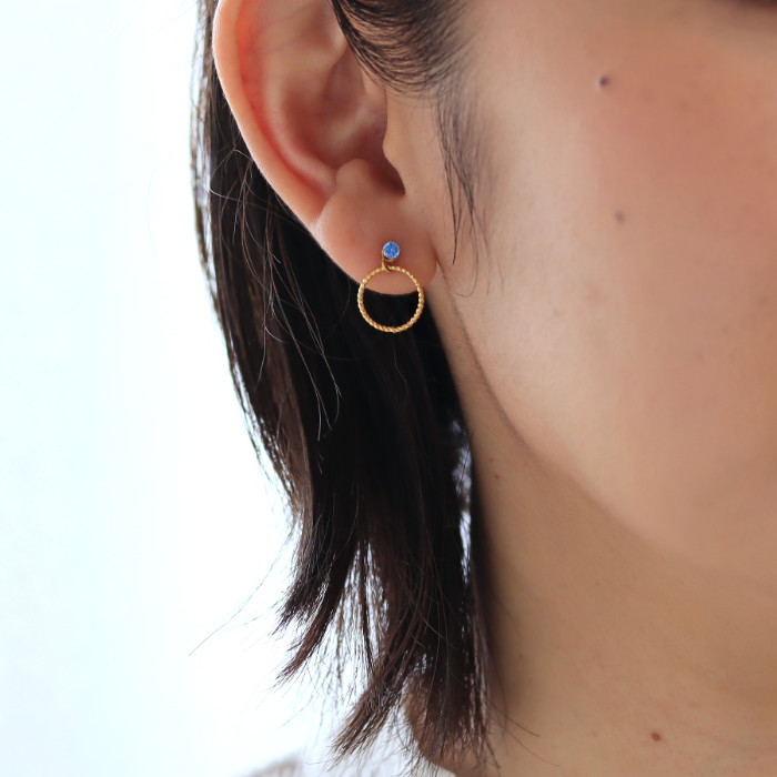 ゴールドリングチャームとブルーダイヤのピアスを耳に着けた女性の耳元画像