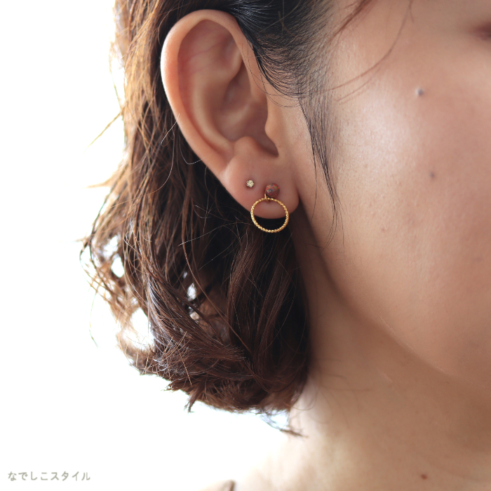 秋色ピアスとリングチャームをつけた女性の耳元画像