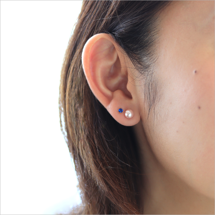 ネイビーのピアスと桜色パールのピアスを着けた女性の耳元画像