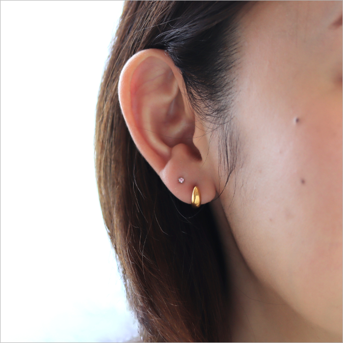 三日月ゴールドのピアスと小粒サイズのサファイヤピンクのピアスを着けた女性の耳元画像