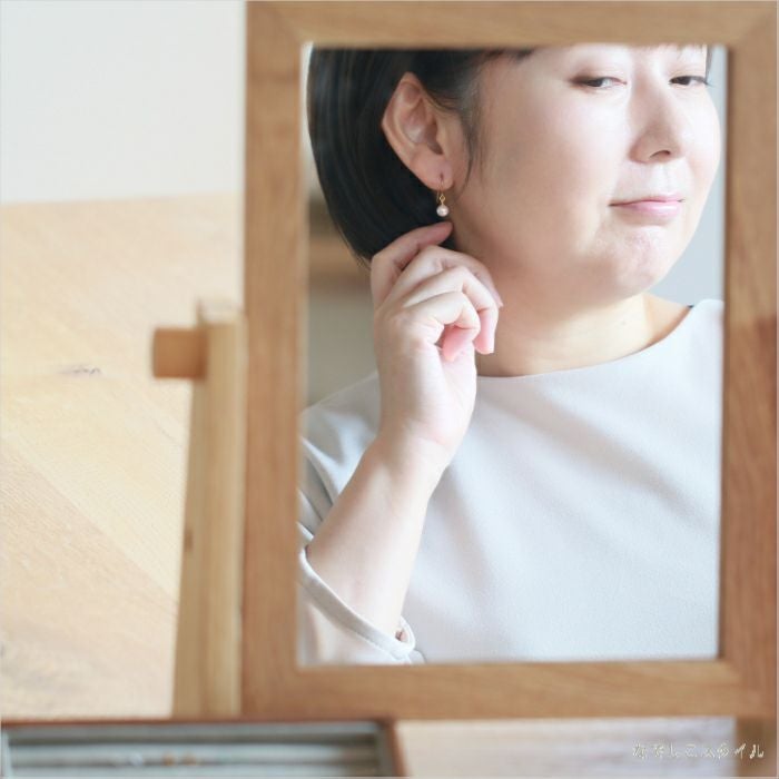 金属アレルギー対応の純チタンフック使用「桜色グラスパール６mm（フック）」の鏡を眺めて微笑む女性画像