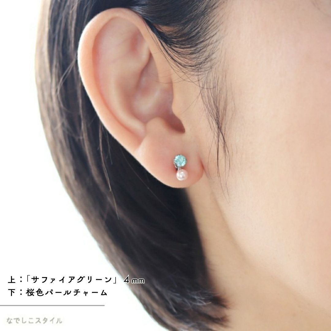 グリーンサファイアのピアスに桜色パールチャームをつけた女性の耳画像