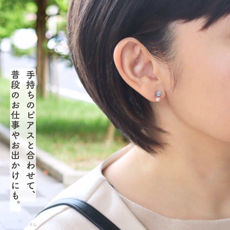 グリーンサファイアのピアスに桜色パールチャームをつけて出勤する女性の耳元画像