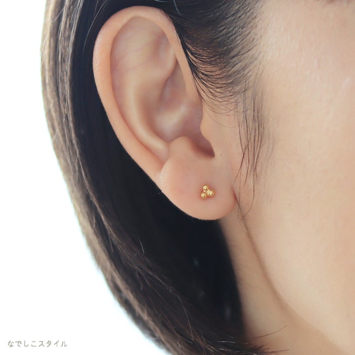 ゴールドカラーのキンモクセイピアスをつけた女性の耳元画像