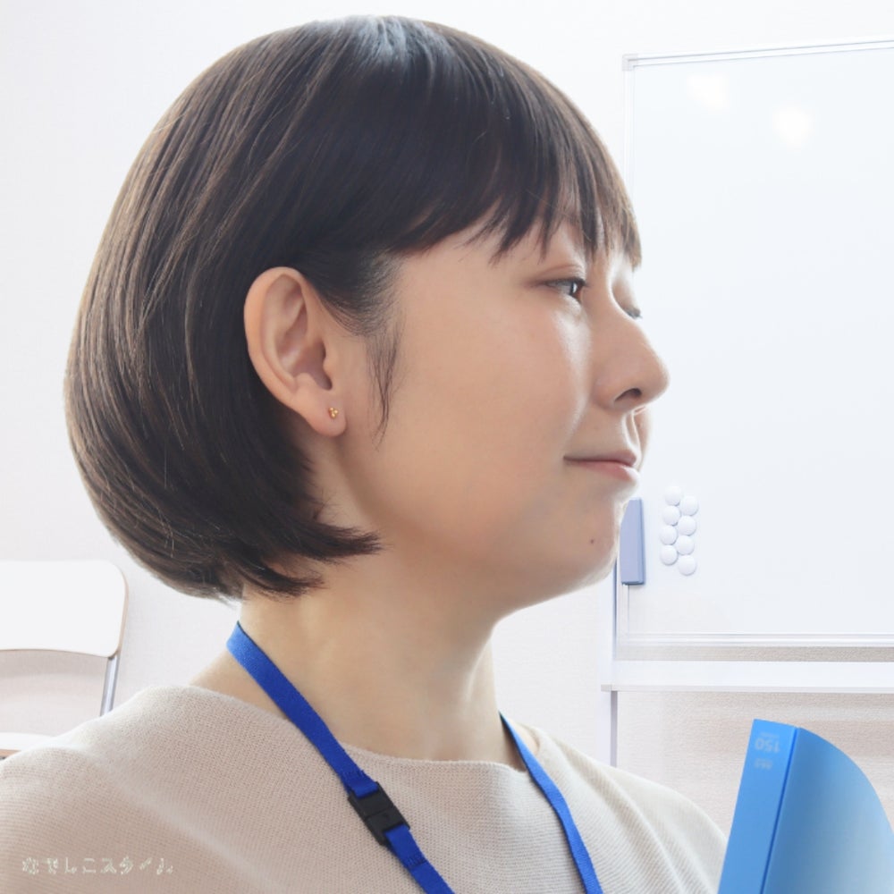 ゴールドカラーのキンモクセイピアスをつけてお仕事をする女性の画像