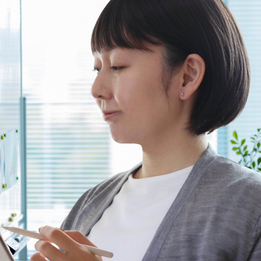 プラチナカラーのキンモクセイピアスをつけてお仕事をする女性の画像