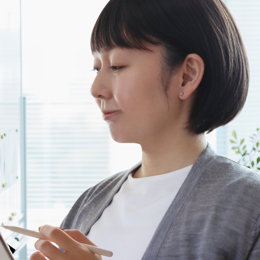 プラチナカラーのキンモクセイピアスをつけてお仕事をする女性の画像