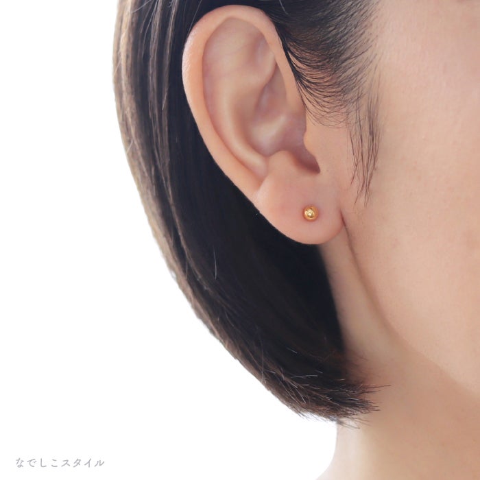 金属部分すべてがチタン純度99.5％の丸玉ピアスゴールドカラーを耳に着けた女性の画像