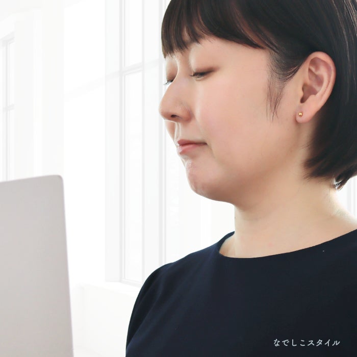 金属部分すべてがチタン純度99.5％の丸玉ピアスゴールドカラーを耳に着けた女性のお仕事イメージ画像