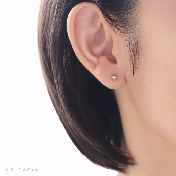 金属部分すべてがチタン純度99.5％の丸玉ピアスプラチナカラーを耳に着けた女性の画像